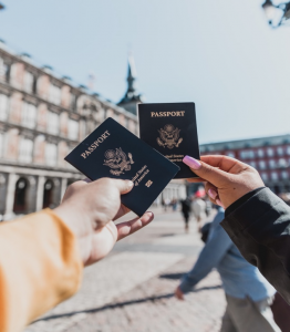 A Faceless Couple Holding Up Their American Passports in Front of a Building