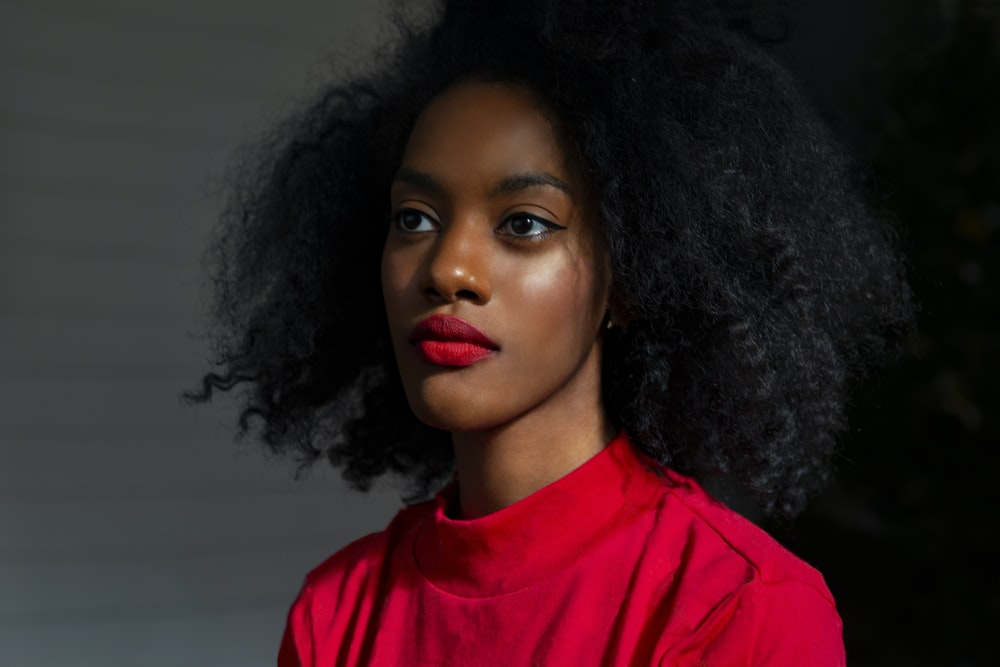 An African American Woman Wearing a Bright Red Top and Matching Lipstick