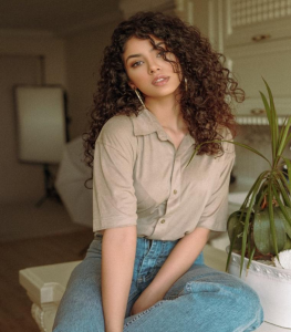 A Woman in a Button-down Top and Jeans with Curly Hair and Neutral Skin Tone