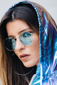 a woman in a shiny blue hoodie and sunglasses